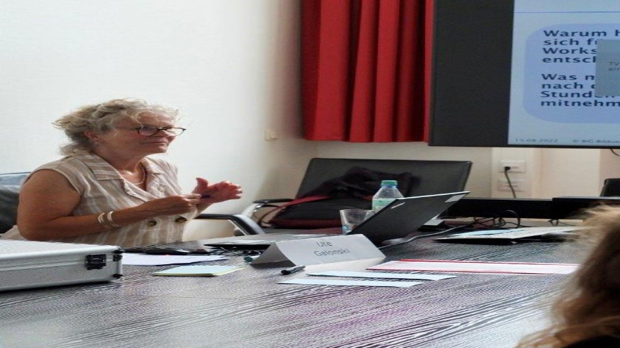 Referentin sitzt vor Laptop im Workshopraum und referiert